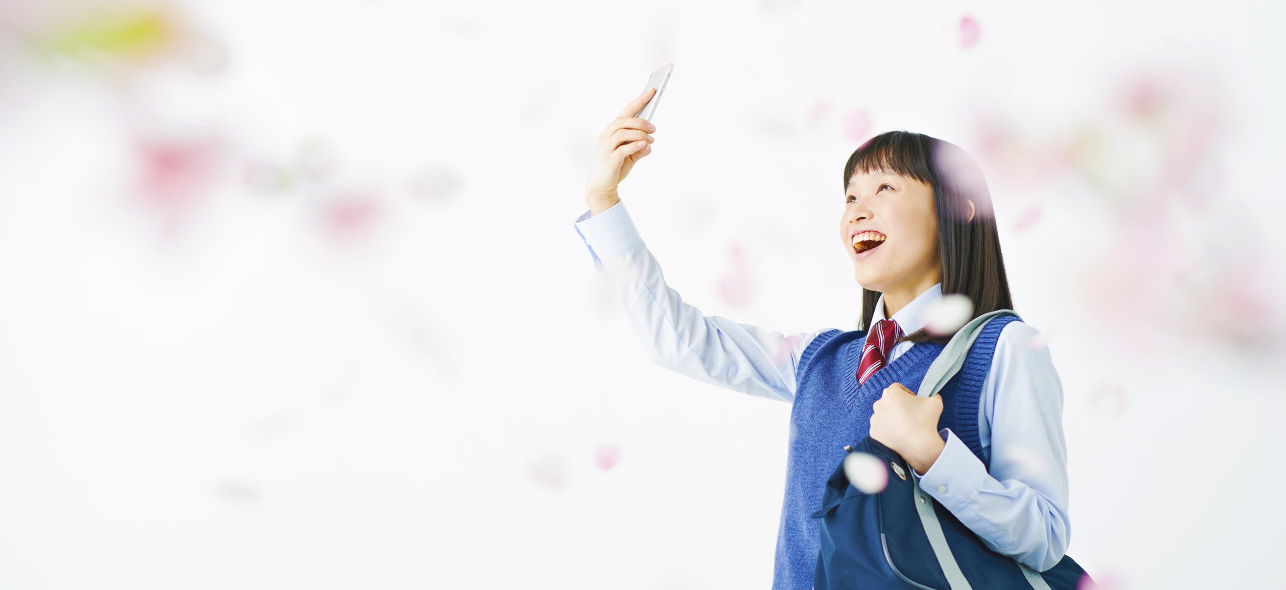 スマートフォンでアプリを起動し笑顔になる学生