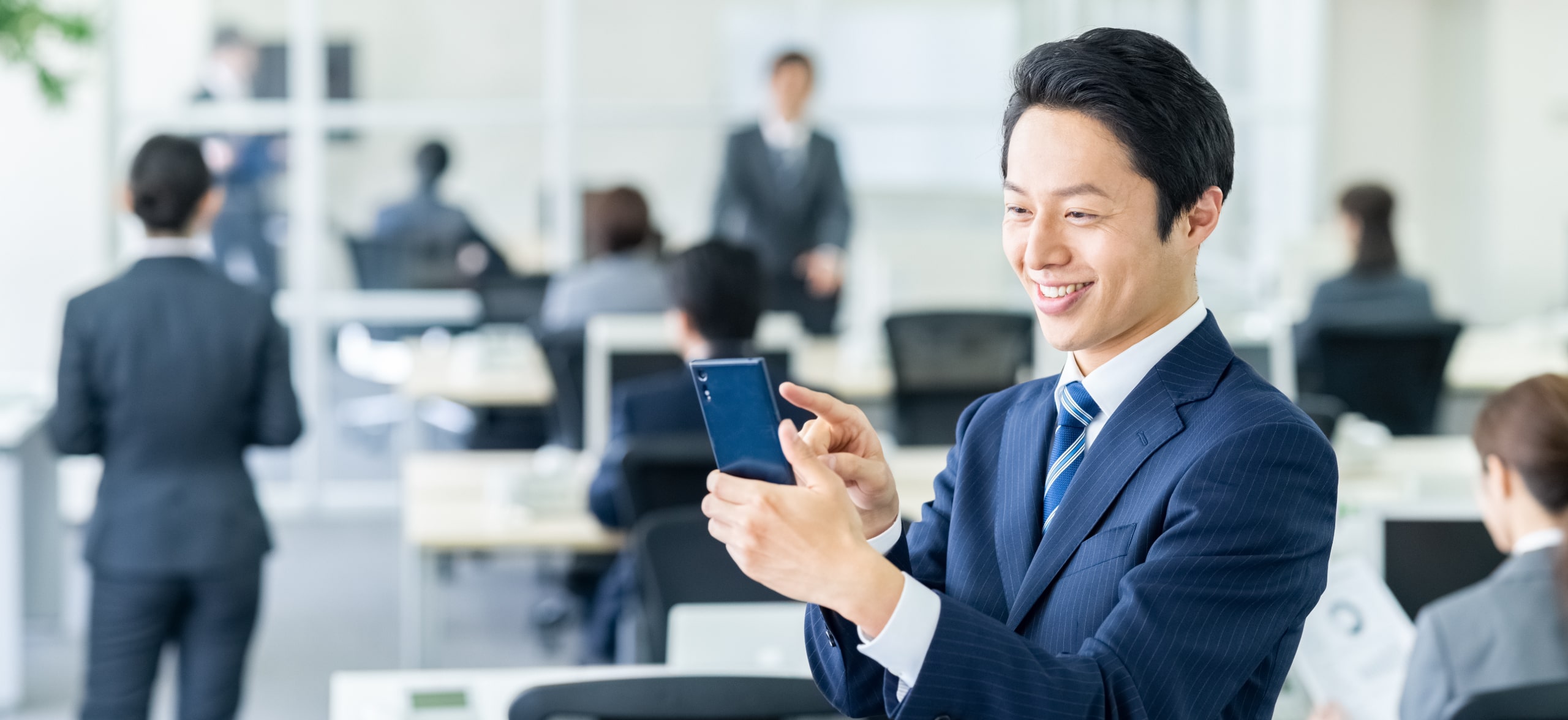 スマートフォンでアプリを起動し笑顔になる社会人