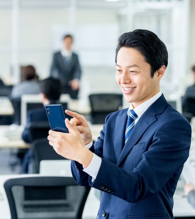 スマートフォンでアプリを起動し笑顔になる社会人