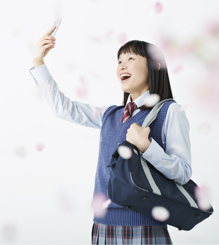 スマートフォンでアプリを起動し笑顔になる学生